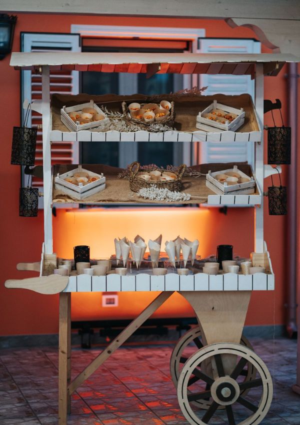 Carretto di legno arancione con dolci e pasticcini per il buffet