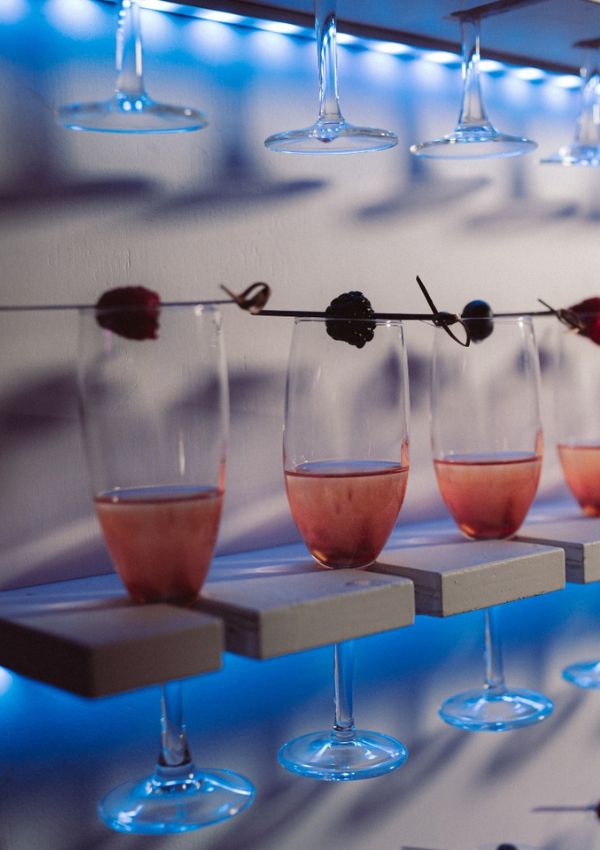 Bicchieri con cocktail rosa su mensole illuminate di azzurro