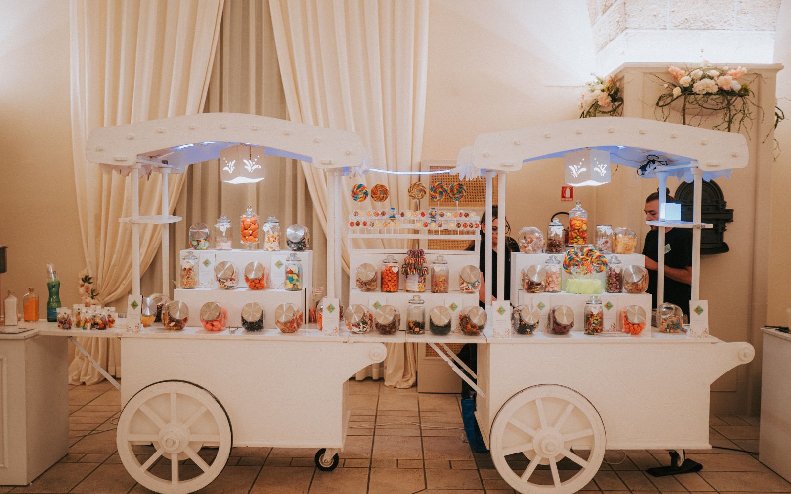 Due carretti bianchi del candy bar allestiti con barattoli di caramelle